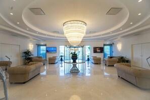 A spacious lobby with a large chandelier, plush seating, and a reflective floor. - Pm Hotel (Catanzaro)