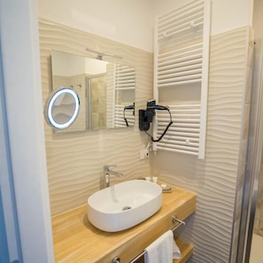 Un baño moderno con un espejo redondo, un lavabo blanco, un perchero y una toalla colgada.