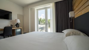A hotel room with a bed, a desk, a chair, a TV, and a view of the outdoors. - Pm Hotel (Catanzaro)