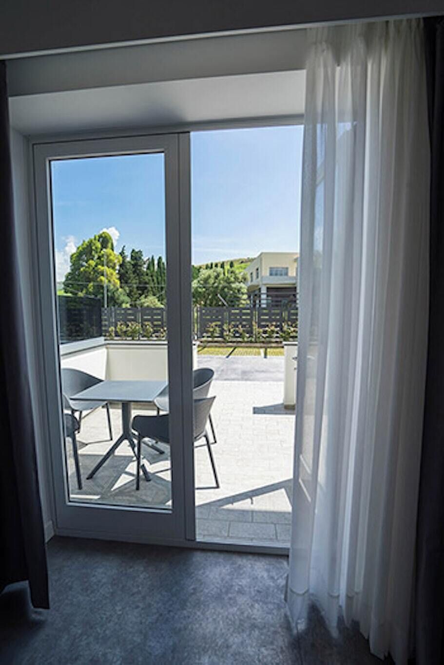 A room with a sliding glass door leading to an outdoor patio area with a table and chairs.