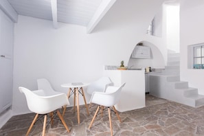 Una cucina moderna con mobili bianchi, pavimento in pietra e una piccola isola con posti a sedere.