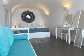 Un dormitorio con cama, mesitas de noche, escritorio, espejo y sofá.