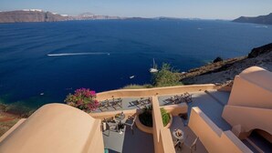 A seaside terrace with outdoor seating and a view of the sea. - Horizon Aeifos (Santorini)