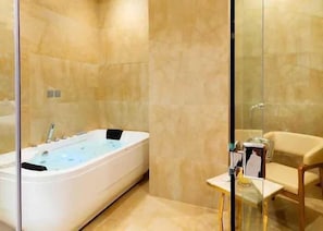 Un baño moderno con una bañera grande, cabina de ducha de vidrio y tocador de madera con espejo.