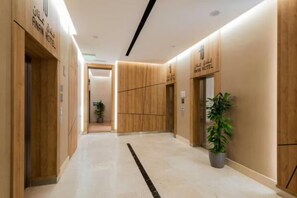 A hotel lobby with a modern design, featuring wooden paneling, a marble floor, and a potted plant. - Sunday Luxury Central Formerly Anan Hotel (Riyadh)