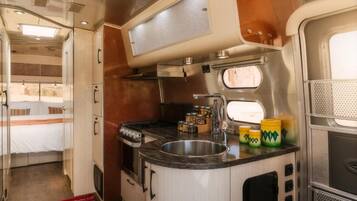 Una cocina compacta con estufa, lavamanos y alacenas.
