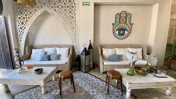 A cozy lounge area with two sofas, a coffee table, and a decorative wall piece. - Layla Tulum Adults Only (Tulum)