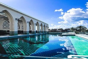 A swimming pool with a checkered pattern, surrounded by arched structures with decorative lighting. - Layla Tulum Adults Only (Tulum)