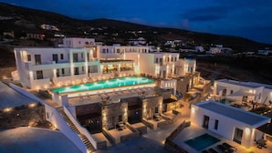 Hotel modern amb una gran piscina, mobiliari exterior i un paisatge de muntanyes al fons.