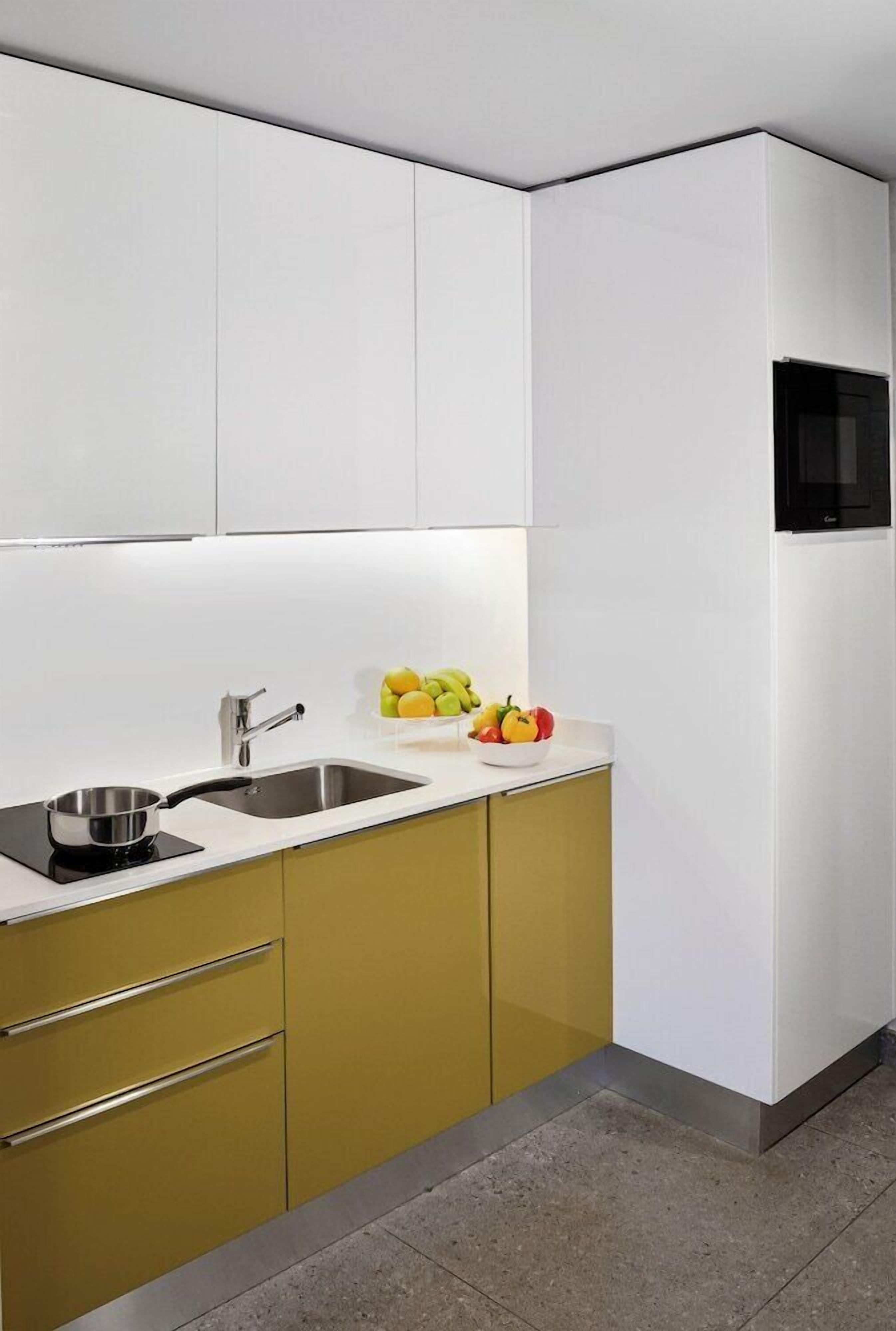 A modern kitchen with white cabinets, a stainless steel sink, and a microwave.