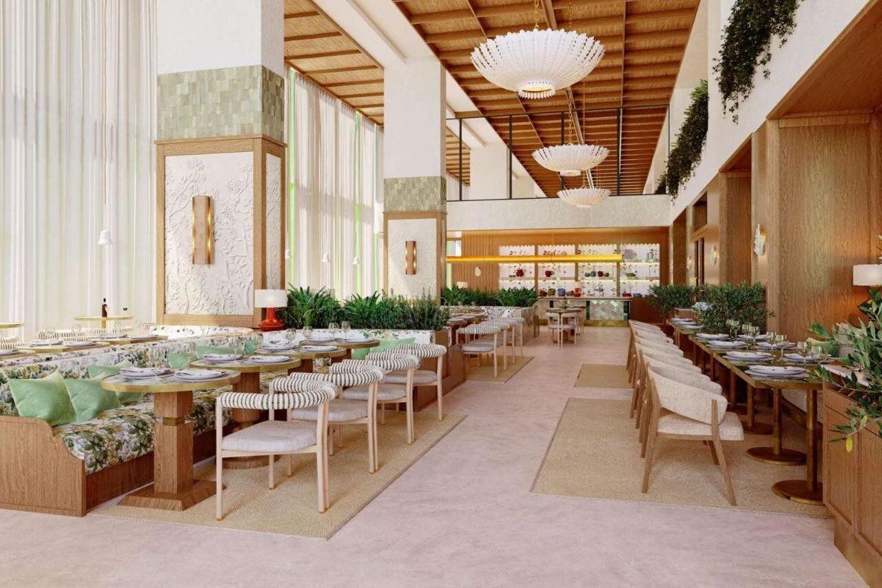 A spacious indoor dining area with long tables, chairs, and hanging pendant lights.