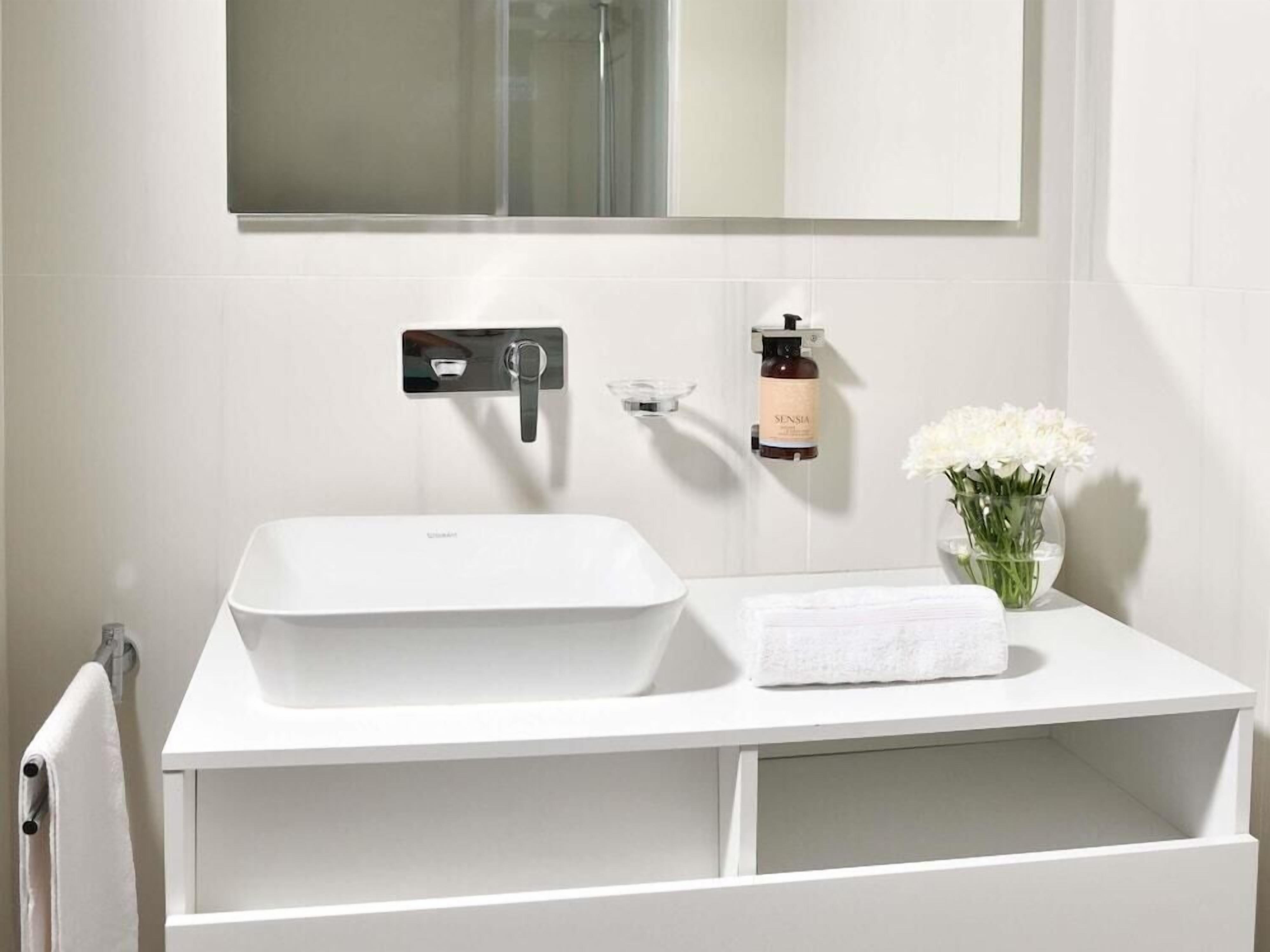 A bathroom with a white sink, a mirror above it, and a towel rack.