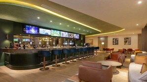 A bar area with a curved counter, multiple bar stools, and a television screen displaying content. - Rixos Radamis Sharm El Sheikh (Sharm El Sheikh)
