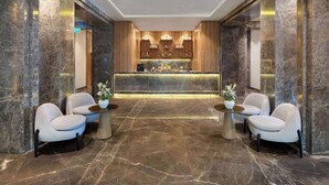 A lobby with marble flooring, a reception desk, and two armchairs with small tables. - Rixos Radamis Sharm El Sheikh (Sharm El Sheikh)