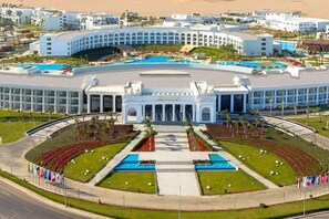 Un hotel modern i gran amb un pati central, diverses piscines i una façana simètrica.