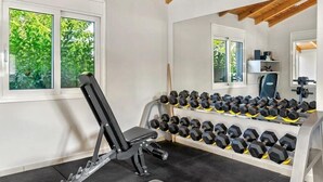 A gym with a rowing machine, dumbbells, and a mirror. - Stefania Beach Resort (Eretria)