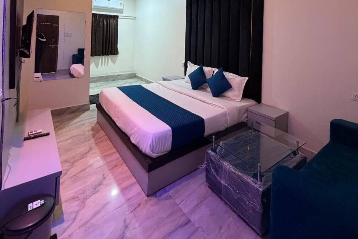 A modern hotel room with a bed, bedside table, and a glass partition.