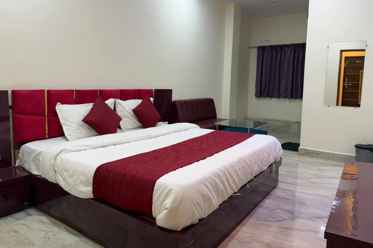 A modern bedroom with a large bed, a nightstand, a glass table, and a view of a bathroom.