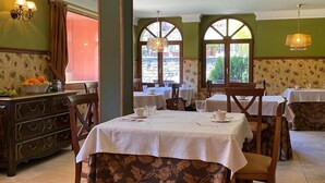 A dining area with tables set for service, a wooden buffet, and large windows with arched tops. - Hotel Finca Malvasia (Cabezon de Liebana)