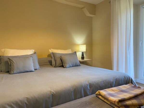 A bedroom with a large bed, two bedside tables, a lamp, and a window with curtains. - Hotel Finca Malvasia (Cabezon de Liebana)