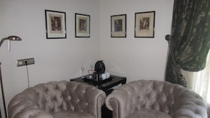 A room with two tufted armchairs, a small table with a coffee maker, and three framed pictures on the wall. - Hotel Finca Malvasia (Cabezon de Liebana)