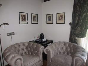 A room with two tufted armchairs, a small table with a coffee maker, and three framed pictures on the wall. - Hotel Finca Malvasia (Cabezon de Liebana)