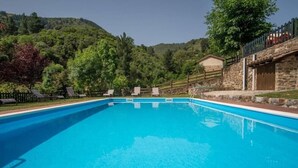 A rectangular swimming pool with a stone wall on one side and a wooden fence on the other. - Hotel Finca Malvasia (Cabezon de Liebana)