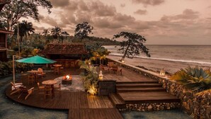 A wooden deck with outdoor seating, a fire pit, and a view of the ocean. - La Coralina Island House -only Adults (Bocas del Toro)
