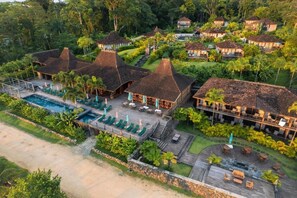 Een resort met meerdere bungalowgebouwen, een zwembad en een fraai onderhouden tuin.