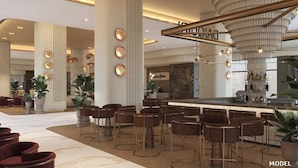 Un hall d’hôtel moderne doté d’un bar, d’espaces aménagés pour s’asseoir et d’un éclairage décoratif.