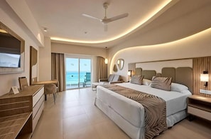 Una habitación de hotel moderna con una cama grande, un escritorio, una silla y un balcón con vistas al océano.