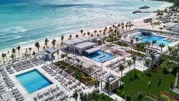 Vue aérienne d’un complexe hôtelier doté de plusieurs piscines, d’un accès à la plage et de palmiers.