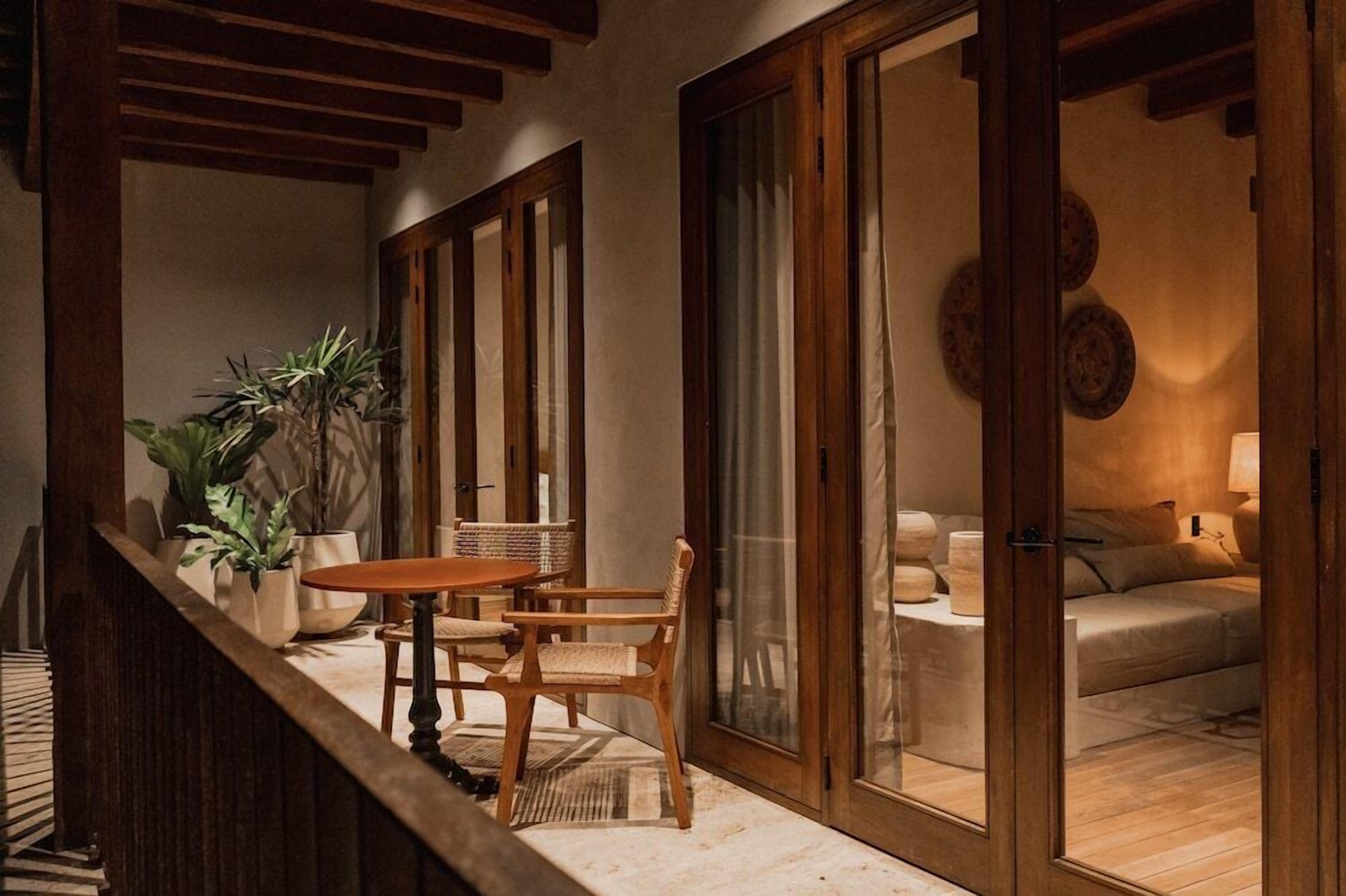 A cozy room with a wooden table and chairs, a sofa, and a large window.
