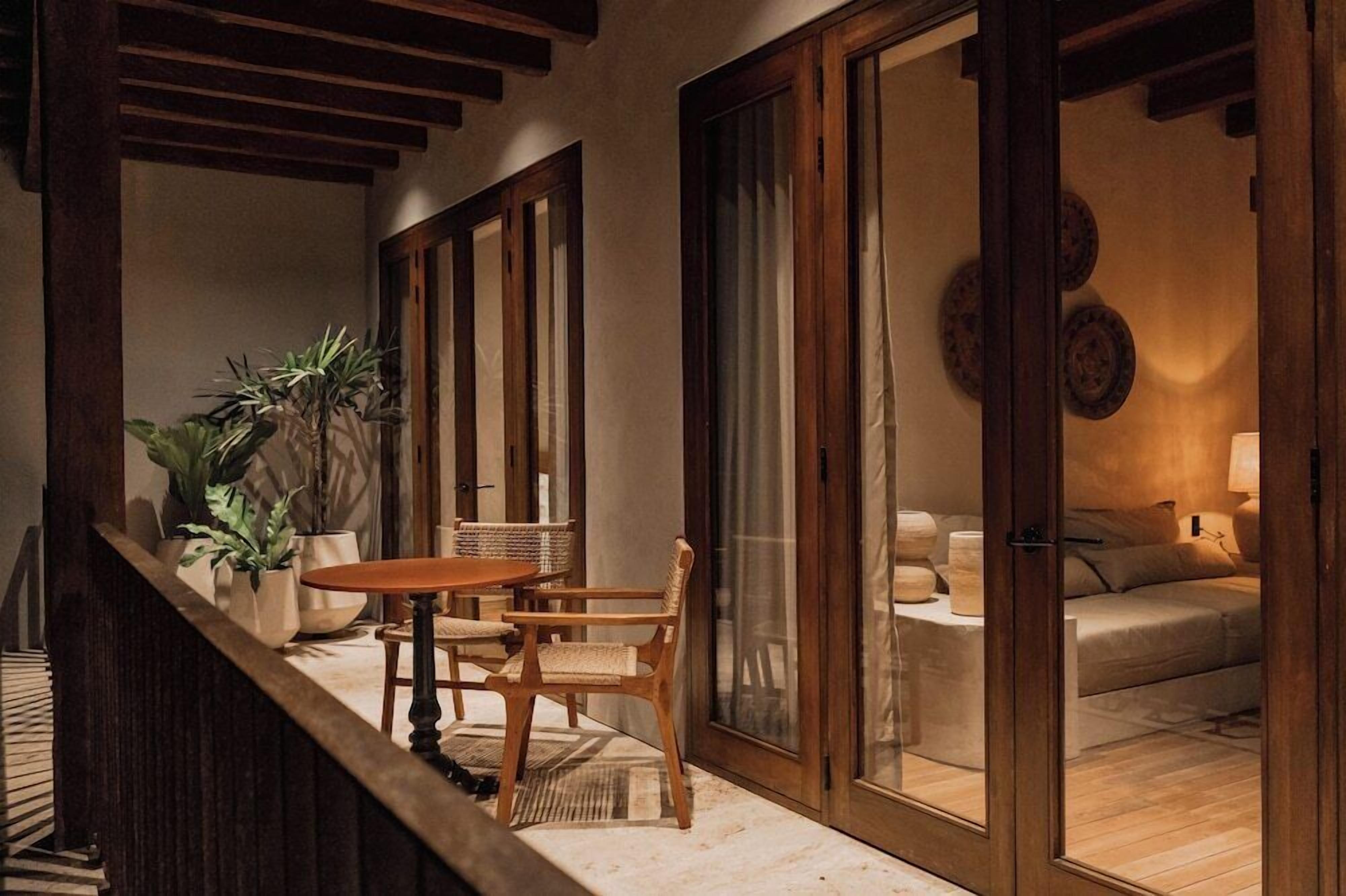 A cozy room with a wooden table and chairs, a sofa, and a large window with curtains.