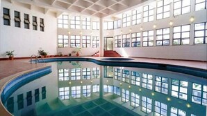Une grande piscine intérieure dotée d’un haut plafond et de nombreuses fenêtres.