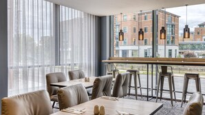 A restaurant with large windows, leather seating, and hanging pendant lights. - Premier Inn York City Centre (York)