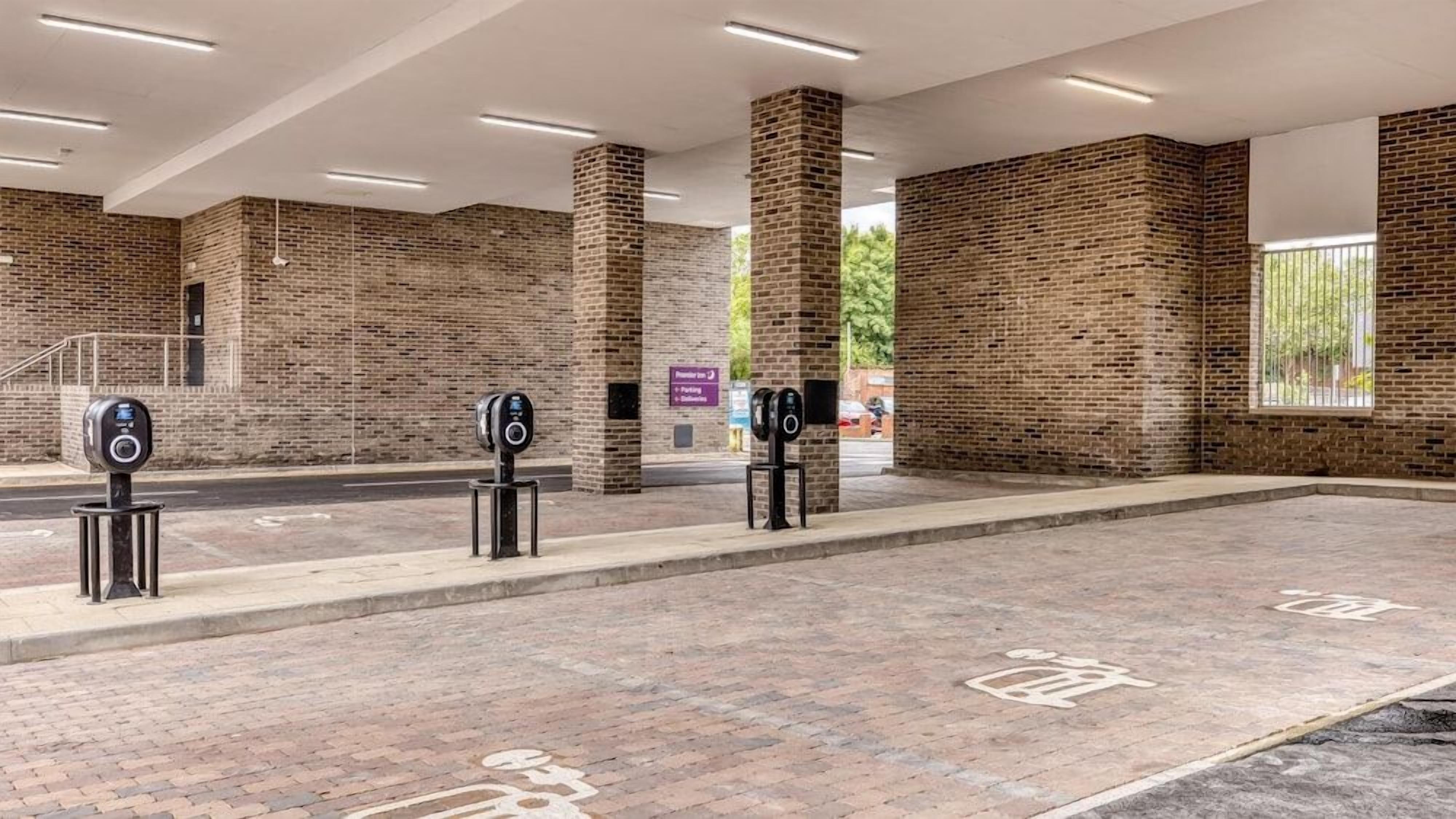 A parking area with brick walls, multiple parking meters, and directional signs.