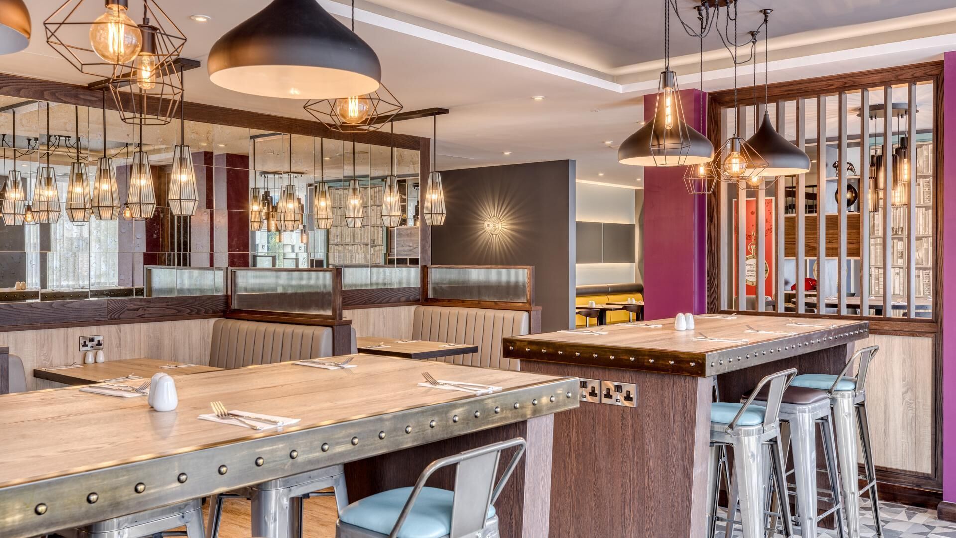 A modern restaurant interior with high tables, bar stools, and pendant lighting.