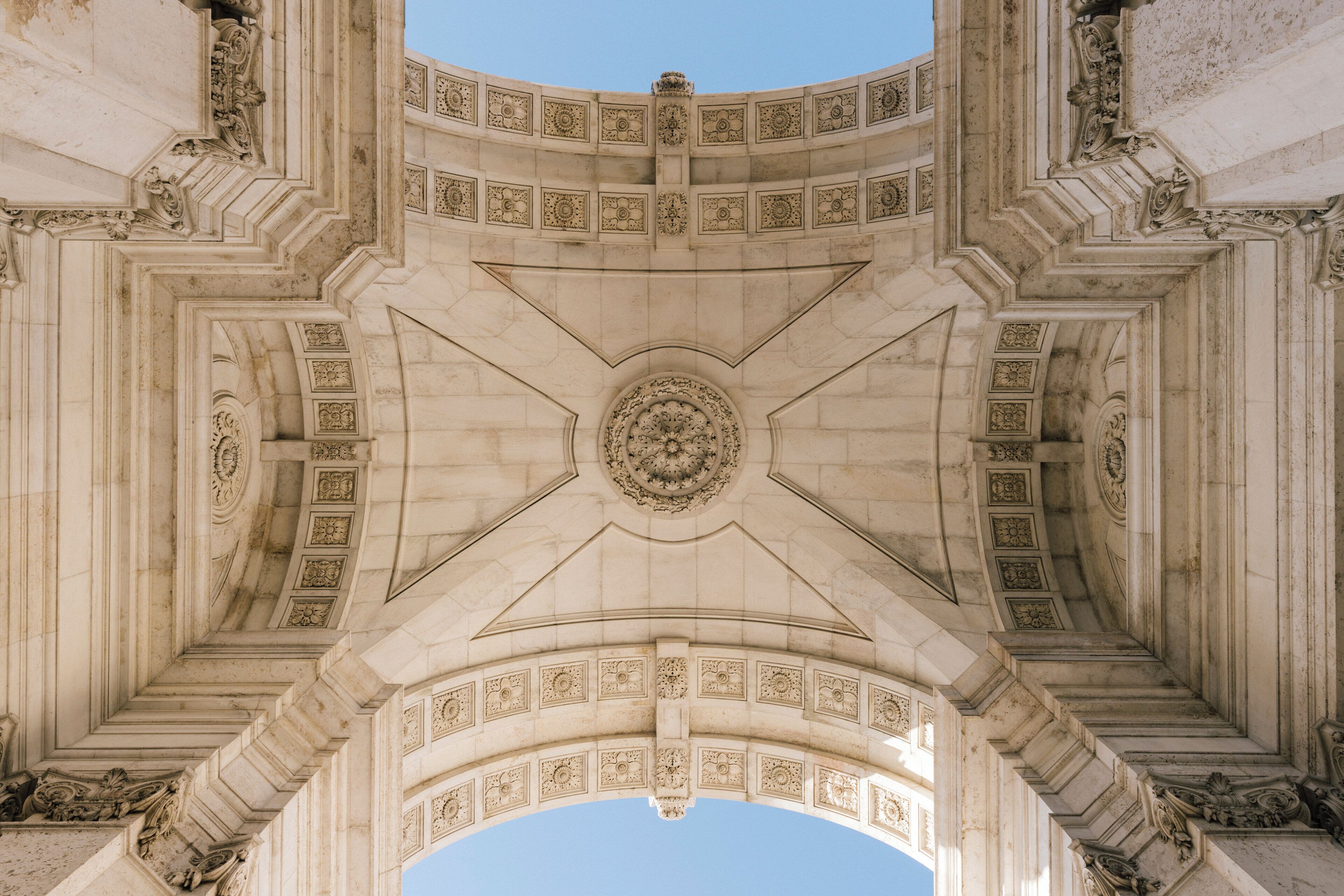 A grand architectural structure with a central circular design, flanked by symmetrical columns and ornate carvings.