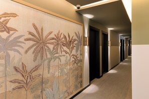 A hallway with a patterned wall, doors, and a security camera. - Pestana Rua Augusta (Lisbon)