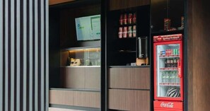A vending machine with various snacks and drinks, a television mounted on the wall, and a wooden cabinet with a glass door. - Bobocabin Ubud, Bali (Tegallalang)