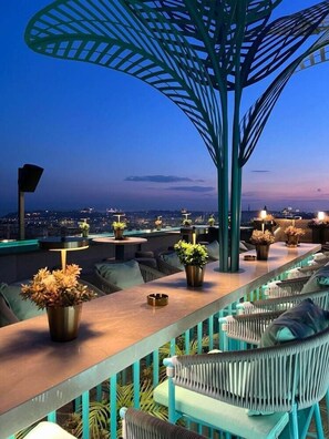 A rooftop bar with outdoor seating, potted plants, and a view of the cityscape at dusk. - Ayramin Exclusive (Istanbul)