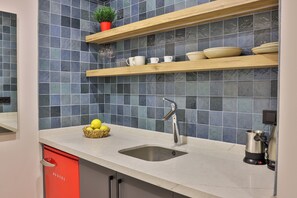 Une cuisine avec un évier, des étagères en bois et un meuble rouge.