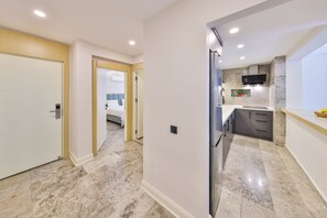 A modern kitchen with marble flooring, a built-in oven, and a microwave. - Sole Suites (Kaş)