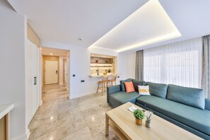 A modern living room with a sofa, a coffee table, and a kitchen area in the background. - Sole Suites (Kaş)