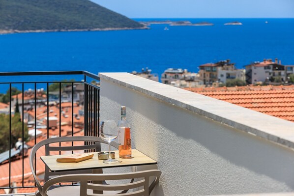 A balcony with a table, a chair, a bottle, and a glass. - Sole Suites (Kaş)