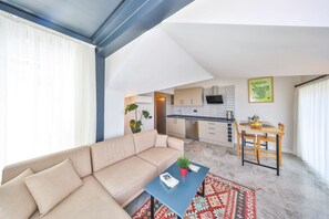 A modern living room with a sofa, a coffee table, and a dining area with a table and chairs. - Sole Suites (Kaş)