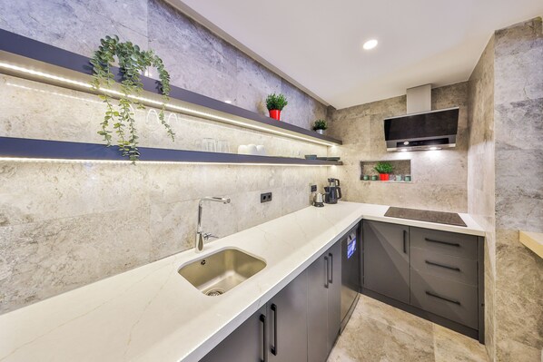 A modern kitchen with a marble countertop, stainless steel sink, and built-in cabinets. - Sole Suites (Kaş)