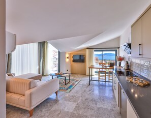 Une chambre d’hôtel moderne dotée d’un canapé, d’une table à manger, d’un coin cuisine et d’un balcon avec vue.