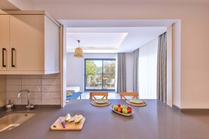 Une cuisine moderne dotée d’un îlot central, d’un coin repas avec des chaises et d’une vue sur l’extérieur.